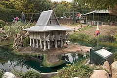 A miniature replicate of the Torogan was built at the center of a pond with the Philippine flag on the right side, surrounded by trees, and located in Canberra, Australia