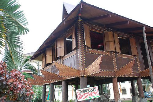 A Torogan replica with the name "TOROGAN" written on board and attached to one of its poles, surrounded with trees, serving as an ancestral house and royal residence of the upper-class Maranao commonly found in Marawi City and other areas in Lanao del Sur province