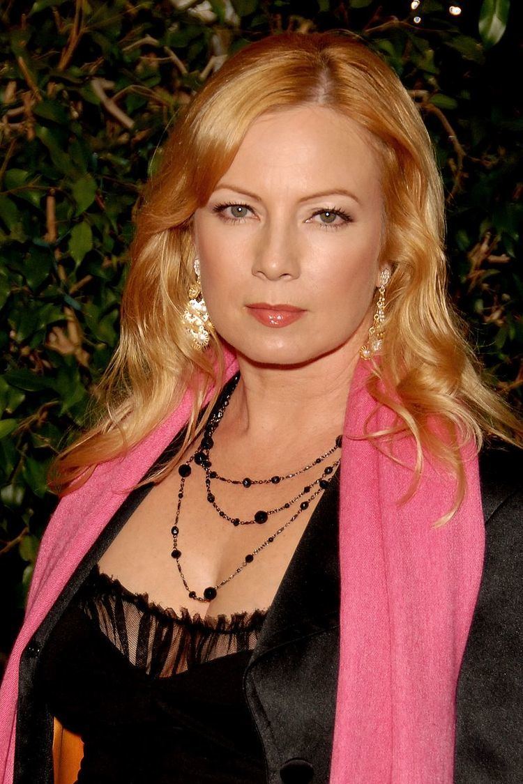 Traci Lords wearing a black blouse, pink scarf, and some pieces of jewelry