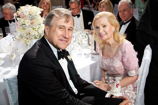 Edward Cox smiling and wearing a black coat, white long sleeve and bow-tie while Tricia Nixon Cox wearing a pink floral dress
