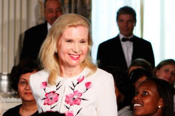 Tricia Nixon Cox smiling while wearing a white and pink floral dress