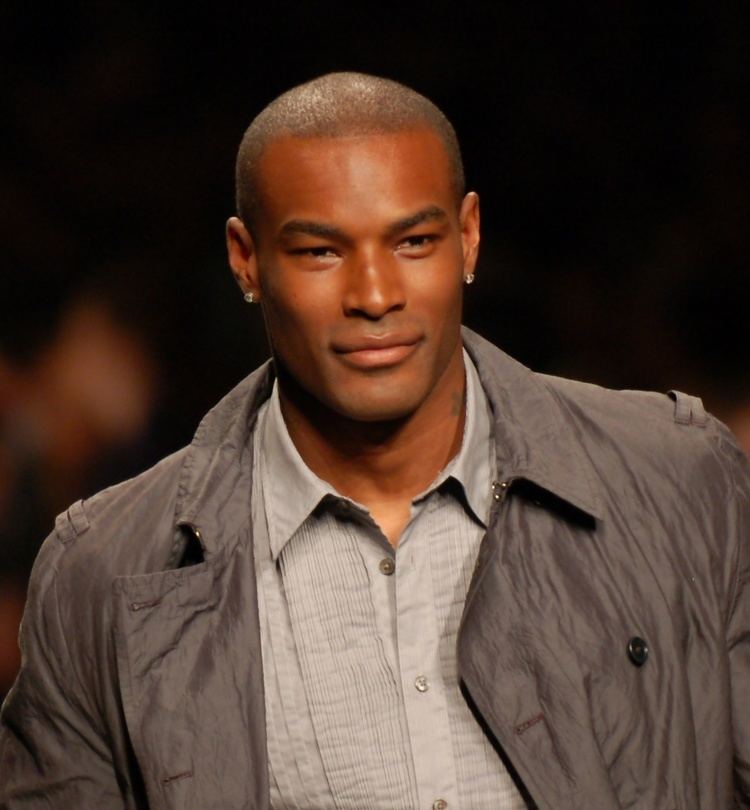 Tyson Beckford smiling during the FashionWeekLive in San Francisco while wearing a gray jacket and light gray polo