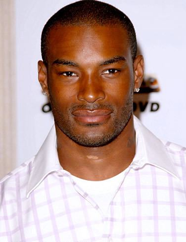 Tyson Beckford smiling while wearing a white and purple polo shirt