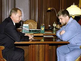 Umar Israilov leaning his arms on the table and having a conversation with Vladimir Putin, Umar wearing a blue shirt and blue pants while Putin wearing a black suit