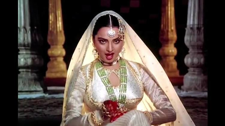 Rekha singing while wearing a beige dress, a veil, and some accessories in a scene from the 1981 film "Umrao Jaan"