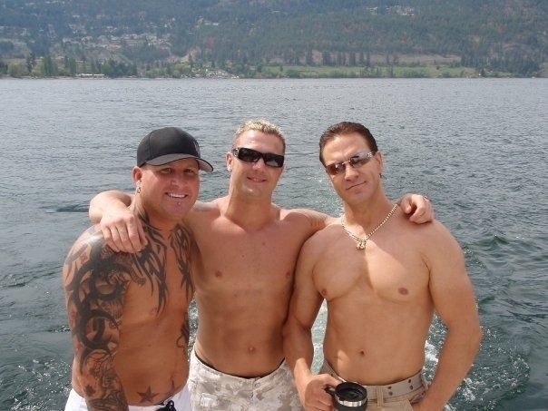 Matt Schrader wearing a cap with two men beside him on the lake