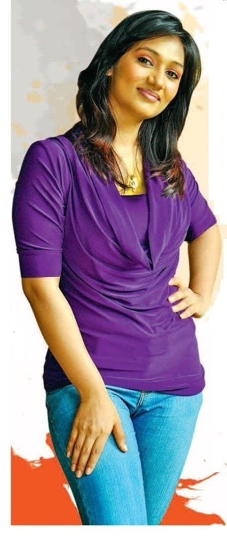 Upeksha Swarnamali smiling with her hand in her waist and wearing a purple shirt and jean pants.