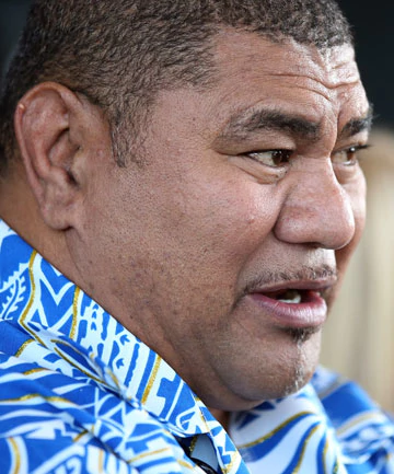 Va'aiga Tuigamala talking in a side view and wearing a blue and white shirt