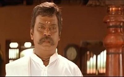 Vijayakanth with a serious face and wearing a white shirt in a movie scene from Vaanathaippola (2000 film).