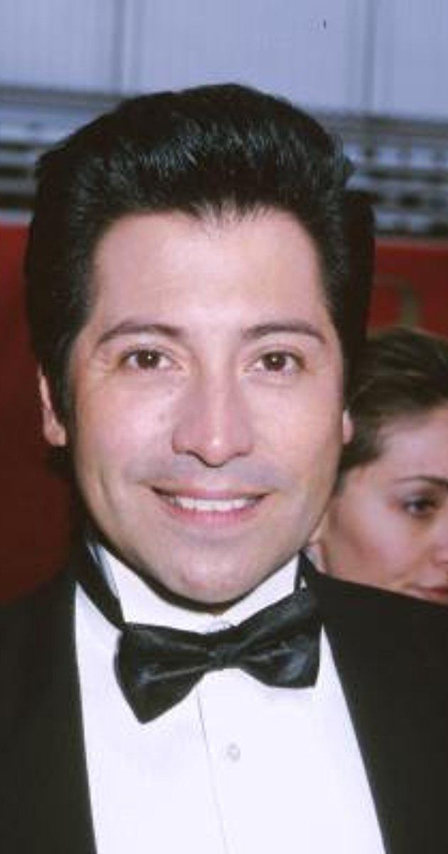 Val Valentino wearing black coat, white long sleeves and bow tie