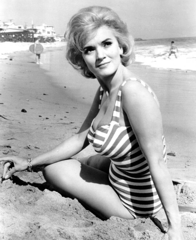 Valora Noland smiling while looking afar and wearing a striped swimsuit.