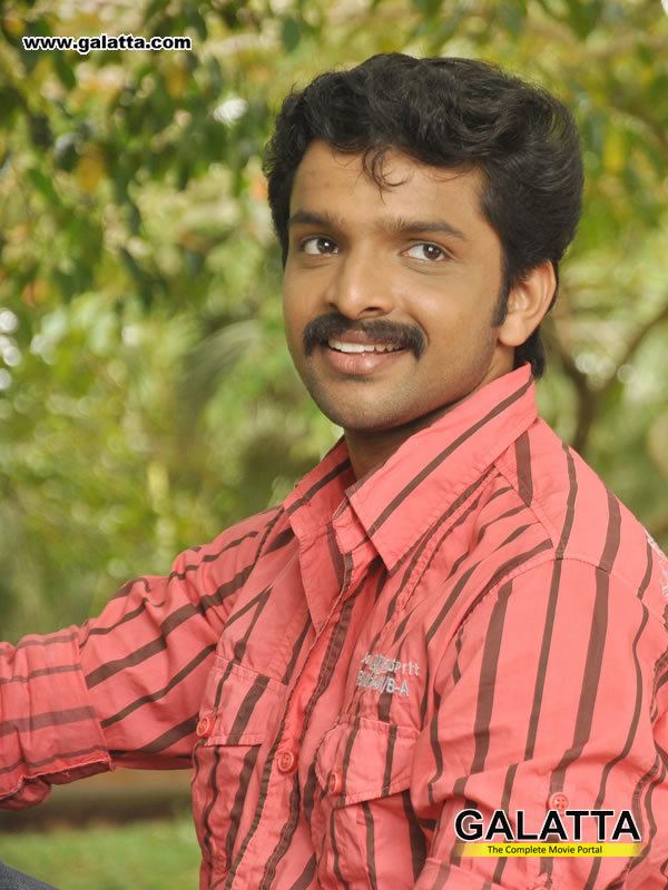 Murali Krishna smiling while looking afar and wearing a pink and brown striped long sleeves