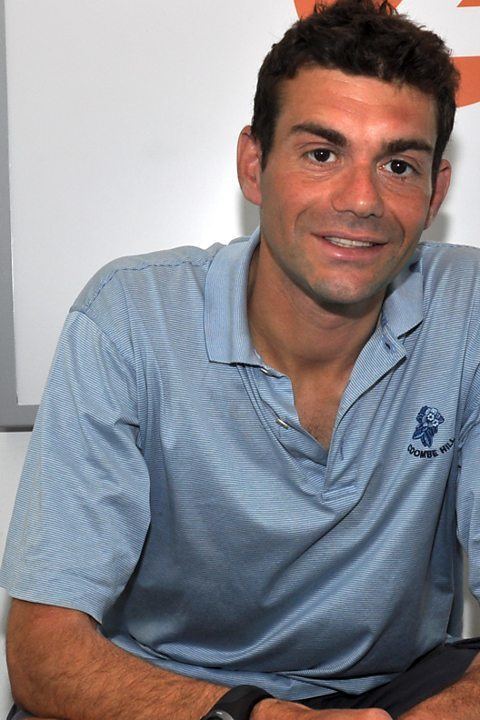 Vassos Alexander smiling while wearing a blue polo shirt