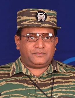 Velupillai Prabhakaran wearing his uniform, a pair of eyeglasses, and a black necklace