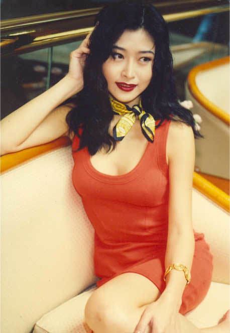 Veronica Yip smiling while wearing an orange mini dress, scarf and bracelet