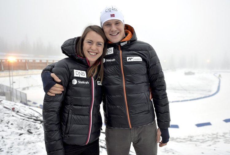 Synnøve Solemdal and Vetle Sjåstad Christiansen smiling while hugging each other (from left to right). Synnøve is a former Norwegian biathlete, with long straight brown hair wearing a black insulated hoodie jacket and Vetle, a Norwegian biathlete, is wearing a white bonnet, and a black and orange insulated hoodie jacket.