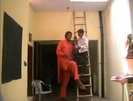 Vikas Uppal standing near a ladder inside his house and wearing a red orange Dhoti.