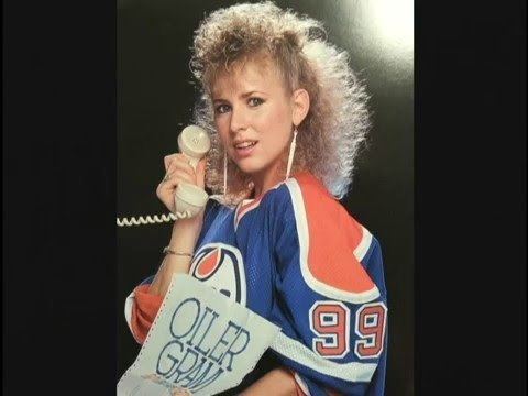Vikki Moss singing while holding a white telephone in her right hand and holding a paper written “Oiler Gram” on a 1985 picture soundtrack titled “If I turn you away”, she has blonde kinky hair, wearing a long dangled earring, and a red and blue jersey with #99 on it