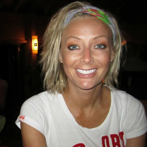 Vikki Thomas smiling while wearing a white and red t-shirt and headband