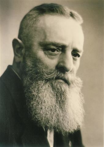 Viktor Schauberger with mustache and long beard while wearing a black coat and white long sleeves