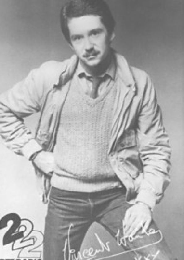 A poster of Vincent Hanley having a mustache and his hand on his waist with his signature at the bottom and wearing a shirt under a vest, a coat, necktie, and pants