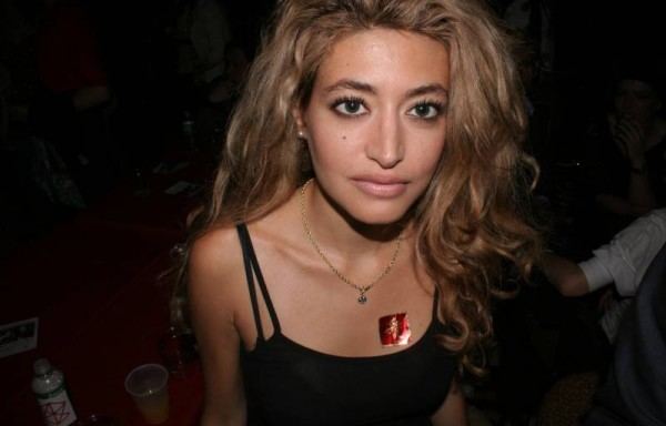 Wafah Dufour with a serious face, curly blonde hair, wearing a necklace, and a black spaghetti top.