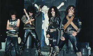 Wagner Lamounier posing with his bandmates and they are wearing a black shirt, black jacket, black pants, bullet belt, and make-up