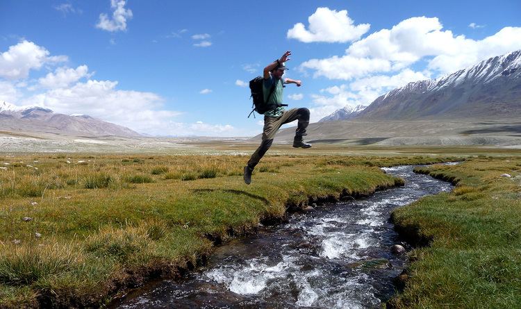 A man jumping over a river in Wakhan Corridor