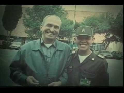 Waldemar Franklin Quintero smiling with a policeman beside him while he is wearing a jacket and striped polo