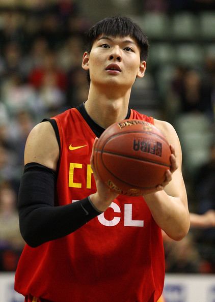 Wang Zhelin holding a ball while wearing a red jersey and black arms sleeve