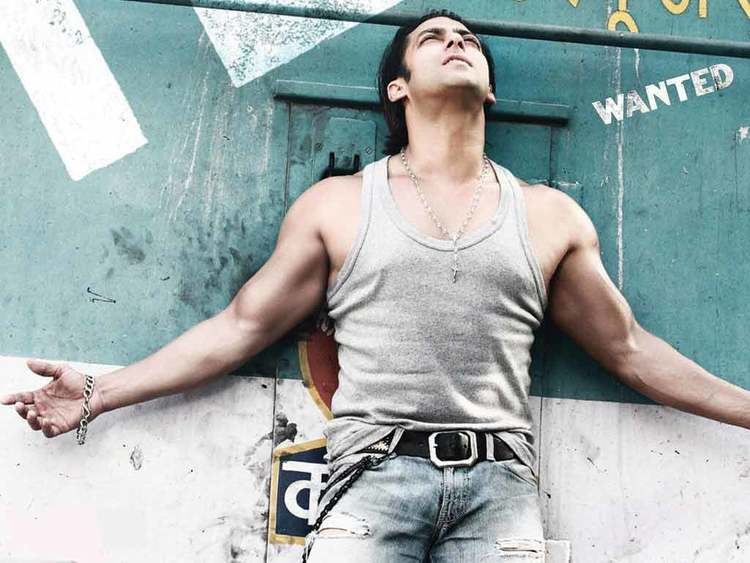 Salman Khan with his arms wide open while wearing a gray sando, jeans, necklace, and bracelet