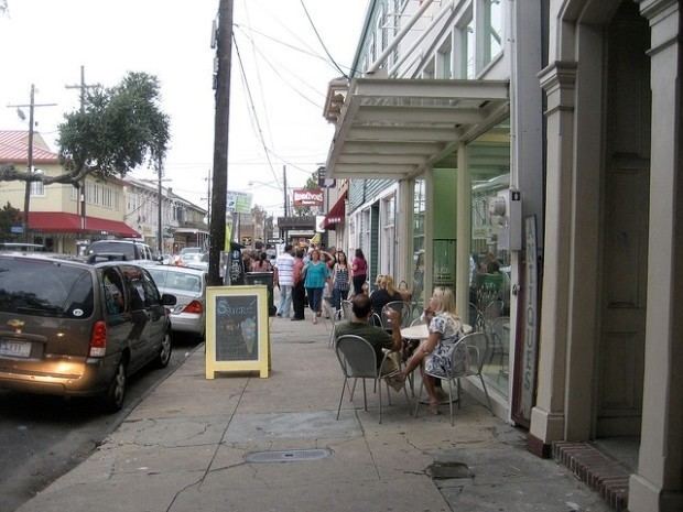 One of the streets in New Orleans where there are houses, restaurants, and cars that parked on the side of the highway