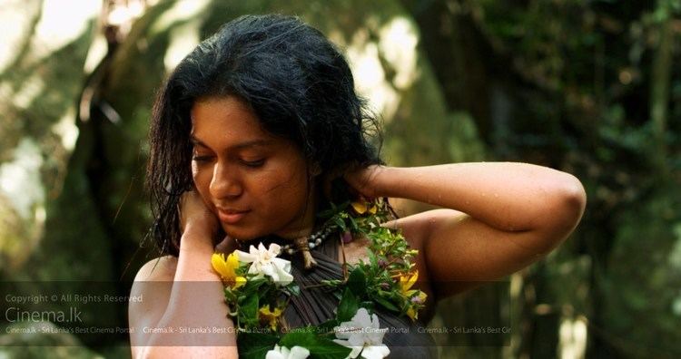 Nadeesha Fonseka as Handuni wearing a garland and black top in a movie scene from the 2014 film WarigaPojja