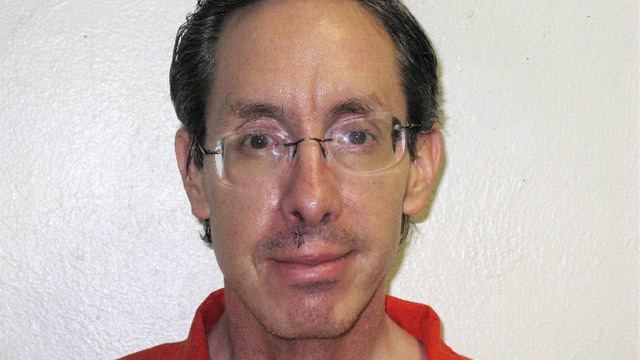 Warren Jeffs is smiling with his black hair and a mustache wearing eyeglass, and a red polo