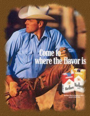 The advertisement poster of Marlboro, on the left, Wayne McLaren is serious, crouching with his right knee on the ground, looking at his right, holding a branding iron with his right hand while left hand holding a cigarette on top of his left knee, has black hair wearing a white cowboy hat, blue long sleeve polo shirt, brown gloves and brown pants, at the right, a wordings written “Come to where the flavor is’’ with red and yellow packs of Marlboro cigarette.
