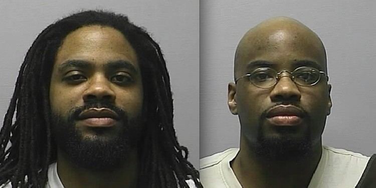 On the left, Reginald Carr with a serious face, dreadlocks hair, a beard and mustache, and wearing a white shirt. On the right, Jonathan Carr with a serious face, bald head, a beard and mustache, wearing eyeglasses, and a white shirt.