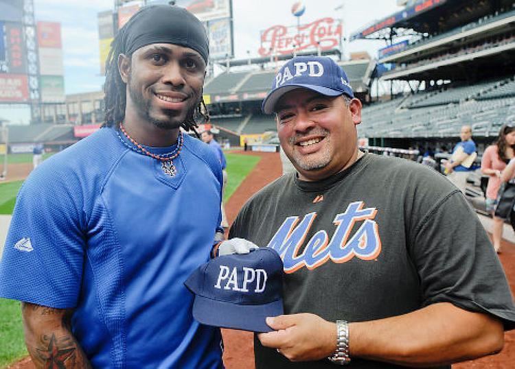 Will Jimeno smiling, wearing a blue cap and a black shirt with a man wearing a blue shirt.