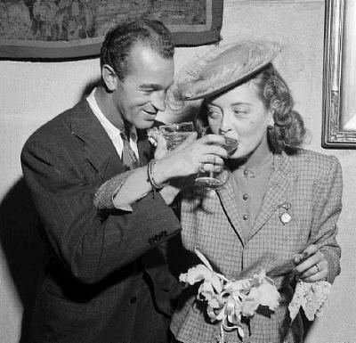 William Grant Sherry drinking wine with her wife Bette Davis wearing a checkered coat and hat