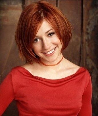 Willow Rosenberg smiling with short hair and wearing a red blouse and a necklace