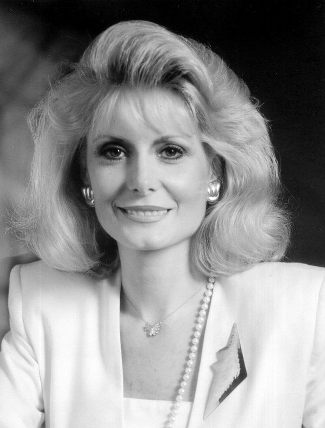 Wilma Smith smiling with a blonde wavy hair and dresses in a formal attire