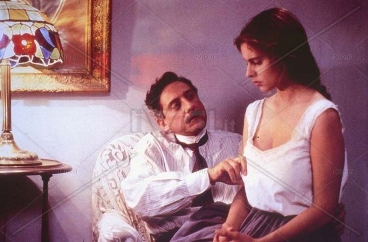 Debora Caprioglio sitting on the man's lap in a movie scene from the 1994 film, With Closed Eyes
