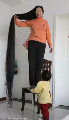 Xie Qiuping smiling while standing on the chair and holding her hair
