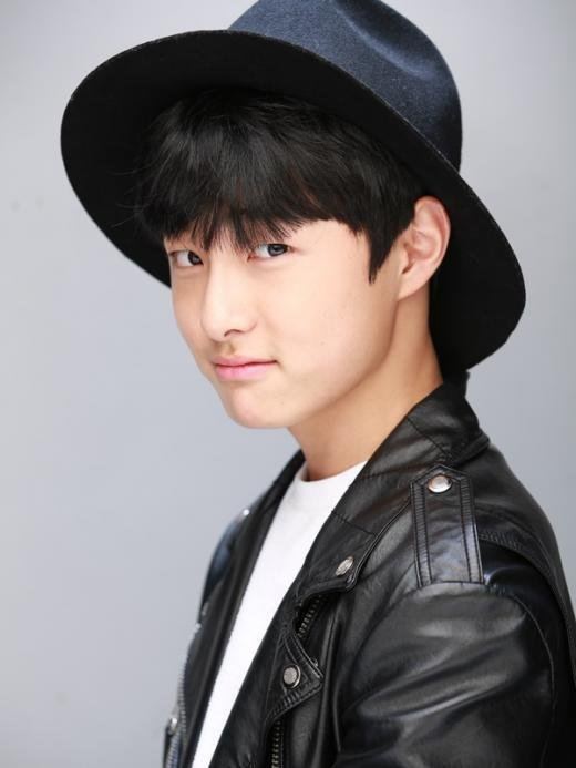 Yoon Chan-young smiling is a South Korean actor with bangs and black hair wearing a black fedora hat and a white shirt and a black leather jacket.