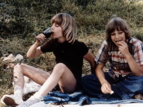 Peter Bjerg drinking some wine while wearing a black shirt and shortless with another boy in a scene from the 1978 film "You Are Not Alone"