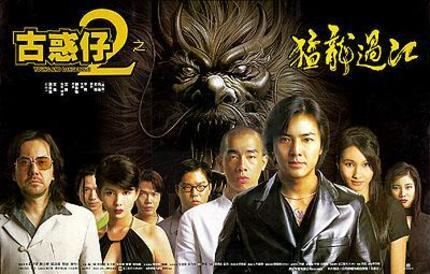 On a movie poster, a lion at the back is opening its mouth, and a man on the left is serious, has black hair, a beard, and a mustache, and wears brown sunglasses, and a gray suit. 2nd from left is a man, serious, has black hair, wearing a green top. 3rd from left a woman is serious, has short black hair, and wears a black sleeveless, cleavage-showing top. 4th from left a man is serious and has black hair. 5th from left a man is serious, has black hair, and wears eyeglasses and a white top. 6th from left a man is serious, bald, and wears a white top. 7th from left a man is smiling, has black hair, and wears a black leather jacket. 8th from left a woman is smiling, has black hair, and wears a black top. On right a woman is serious, has black hair, wearing a black top.