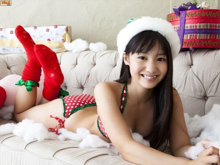 Yui Koike smiling, wearing red polka dots swimsuit, red socks while lying on a couch.