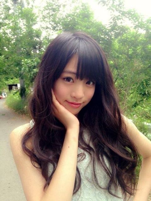 Yuumi Shida posing with a cute smile and her hand in her chin while wearing a white sleeveless dress.