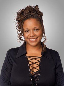 Yvette Wilson smiling with braided hair while wearing a black blouse