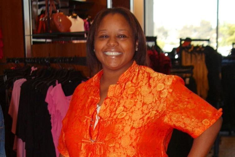 Yvette Wilson with a big smile while wearing an orange blouse