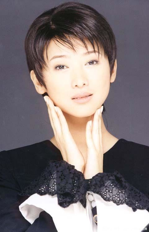 Yvonne Yung smiling with her hands in her chin and having a short hairstyle while wearing a black dress.
